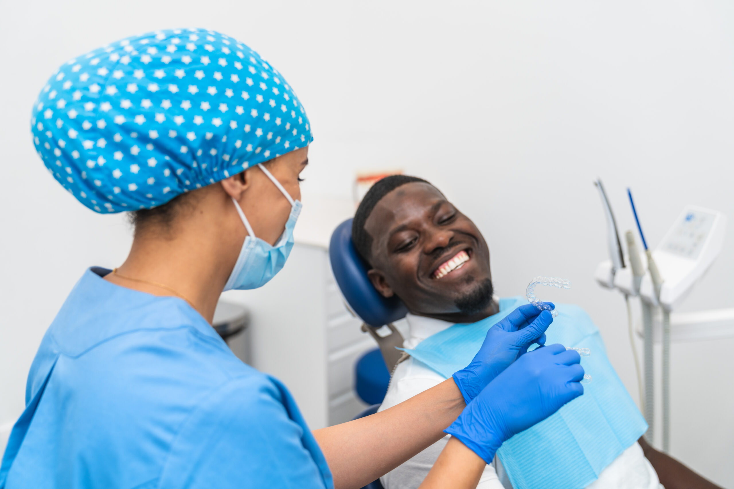 Dental hygienist explaining the use of a retainer to a patient during a checkup in the clinic.